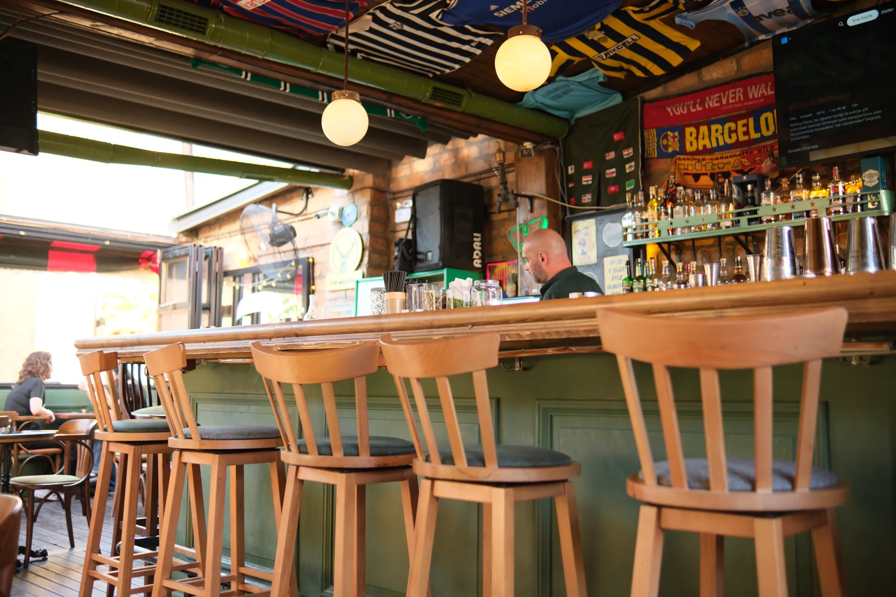 Dublin’in yeşil barı, ahşap bar sandalyeleri ve tavandaki futbol formaları